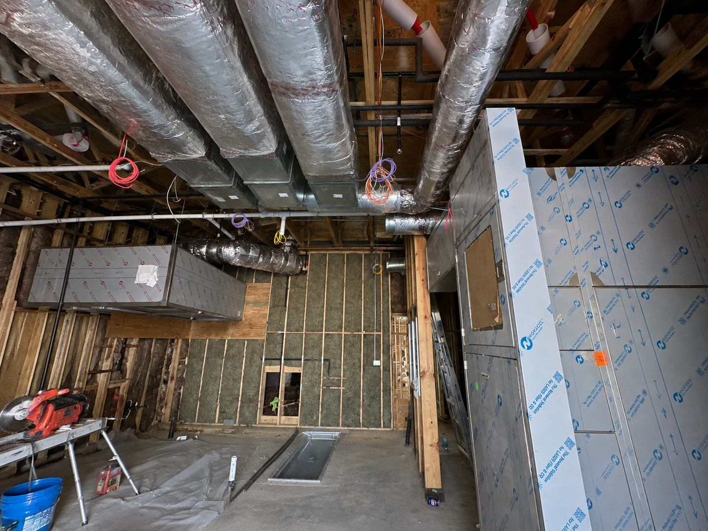 Interior rough-in phase at Olive Garden Selma NC — overhead plumbing infrastructure, framing, and insulation board installation
